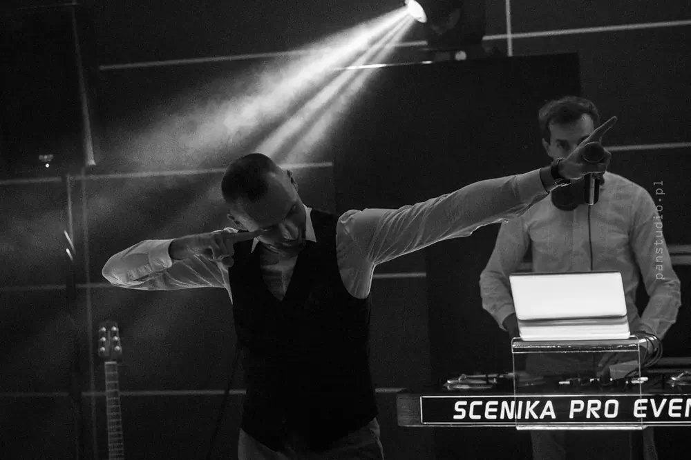 Dwóch DJ-ów przy konsolecie w snopie światła i dymie, zdjęcie czarno-białe