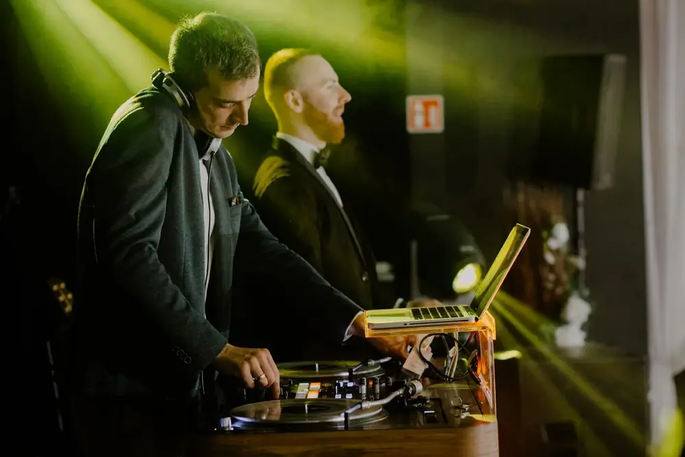 Dwóch DJ-ów przy konsolecie w zielonym świetle